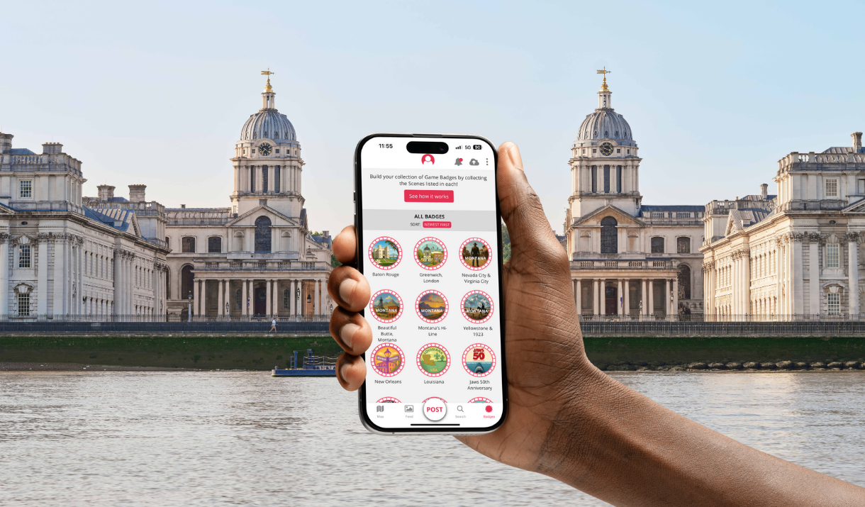 Hand holds up phone in front of Greenwich showing badges on SetJetters app